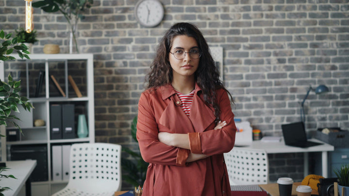 Frustrated woman with arms crossed in front of an office setup